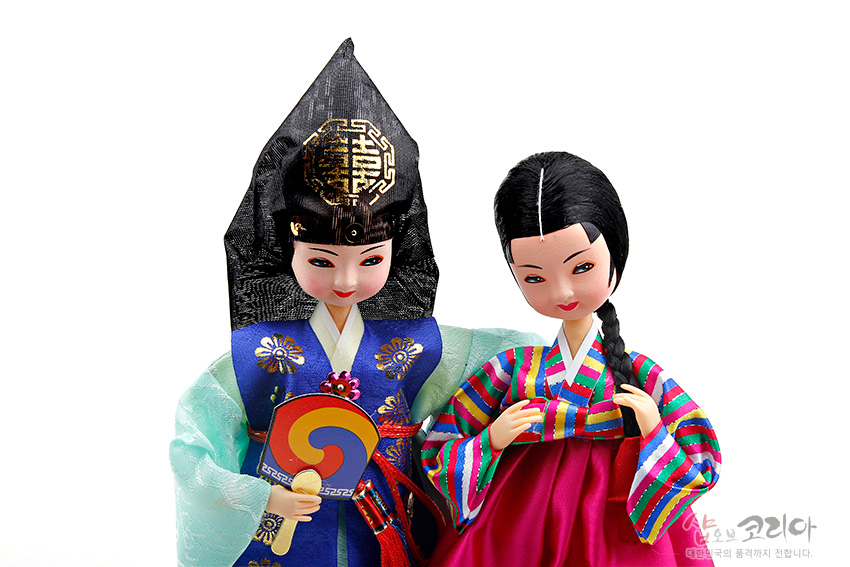 [텍스트: 샵오브코리아 대한민국의 품격까지 전합니다.] 비단 재질 한복을 입은 도령·아씨 인형, 금박 문양 갓과 태극문양 부채, 색동저고리와 자수 조끼가 돋보이는 전통 복식 표현