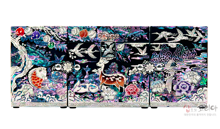 흑색 옻칠 바탕 위 자개 상감 기법으로 사슴, 학, 물고기와 소나무·산수·구름, 모란과 과실 문양을 화려한 오색광으로 표현한 3폭 쌍합 보석함 정면 이미지 설명