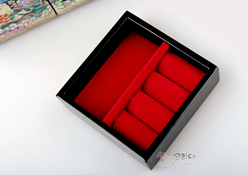 [텍스트: 샵오브코리아 대한민국의 품격까지 전합니다.] 흑색 옻칠 외곽과 붉은 펠트 소재 내부, 반지 수납용 칸막이와 쿠션이 있는 사각 보석함 내부 구조 묘사