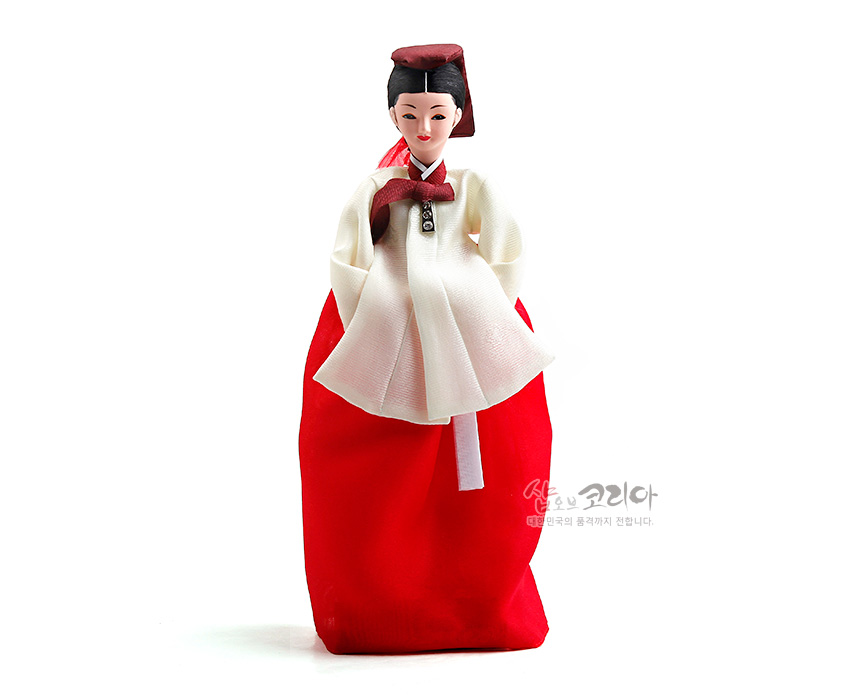 [텍스트: 샵오브코리아 대한민국의 품격까지 전합니다.] 비단 느낌의 흰 저고리와 붉은 치마, 자주색 고름과 관을 쓴 의녀 대장금 한복인형 모습