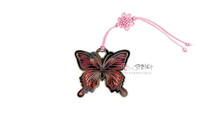 [텍스트: 샵오브코리아 대한민국의 품격까지 전합니다.] 금장 금속으로 제작된 나비 모양 책갈피와 핑크색 전통 매듭 끈, 핑크·청록 그러데이션 색채와 섬세한 날개 문양 장식