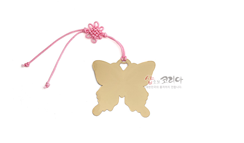 [텍스트: 샵 오브 코리아 대한민국의 품격까지 전합니다.] 금장 금속으로 제작된 나비 형태 책갈피와 분홍색 전통 매듭 장식 끈 구성 이미지