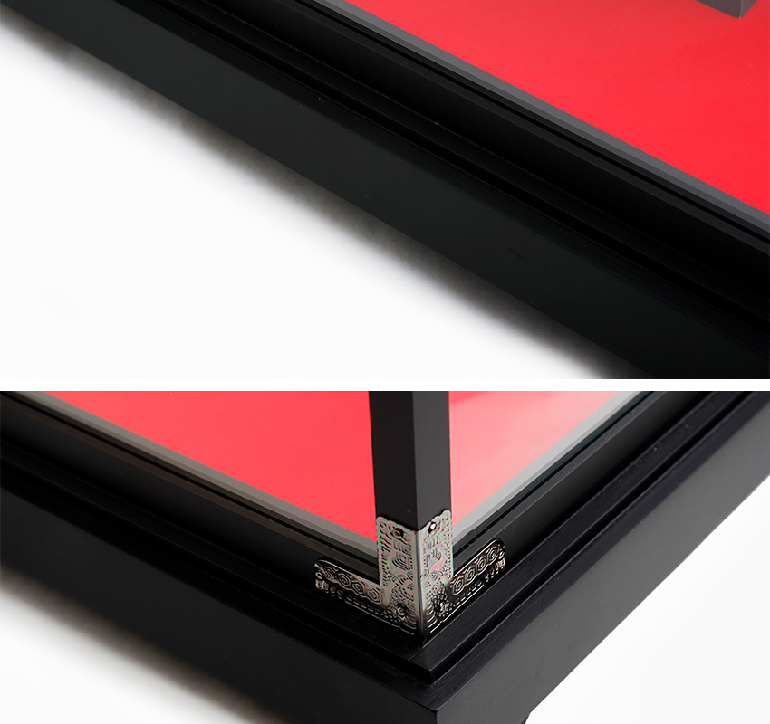 검은색 목재와 투명 유리 조합 쇼케이스, 내부 붉은 바탕과 모서리 금속 장식, 전통 문양 양각 처리된 받침대 디테일 강조 구성