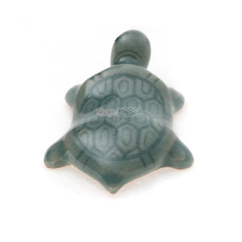 청자 재질로 제작된 거북 모양 수저받침, 옅은 청록색 바탕에 거북 등껍질 육각 문양이 은은하게 새겨진 디자인.