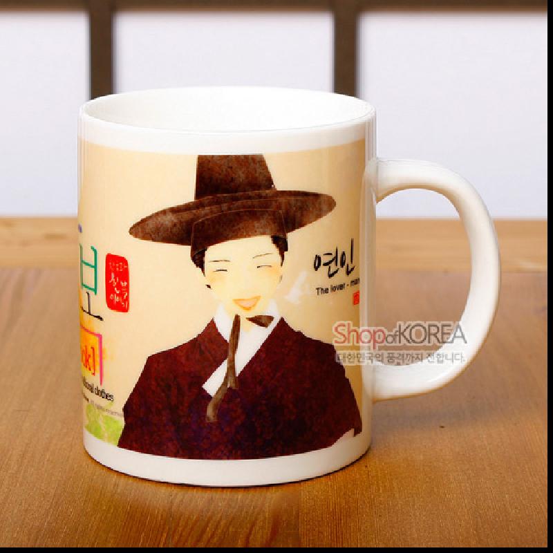 한복과 갓을 쓴 남성 일러스트가 인쇄된 도자기 머그컵, 베이지·갈색 계열의 따뜻한 색감과 한글·한자 서체 장식이 특징인 디자인.