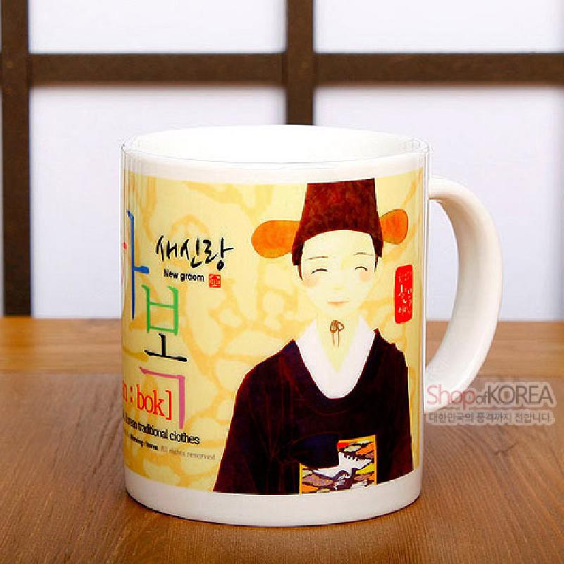 한복 차림 새신랑 일러스트와 한글·영문 타이포그래피가 연노랑 배경 위에 인쇄된 세라믹 머그컵. 한복 차림 새신랑 일러스트와 한글·영문 타이포그래피가 연노랑 배경 위에 인쇄된 세라믹 머그컵.