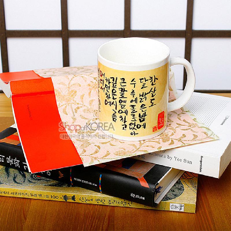 아이보리 바탕에 노란 그라데이션과 흑색 한글 서예문이 인쇄된 도자기 머그컵.