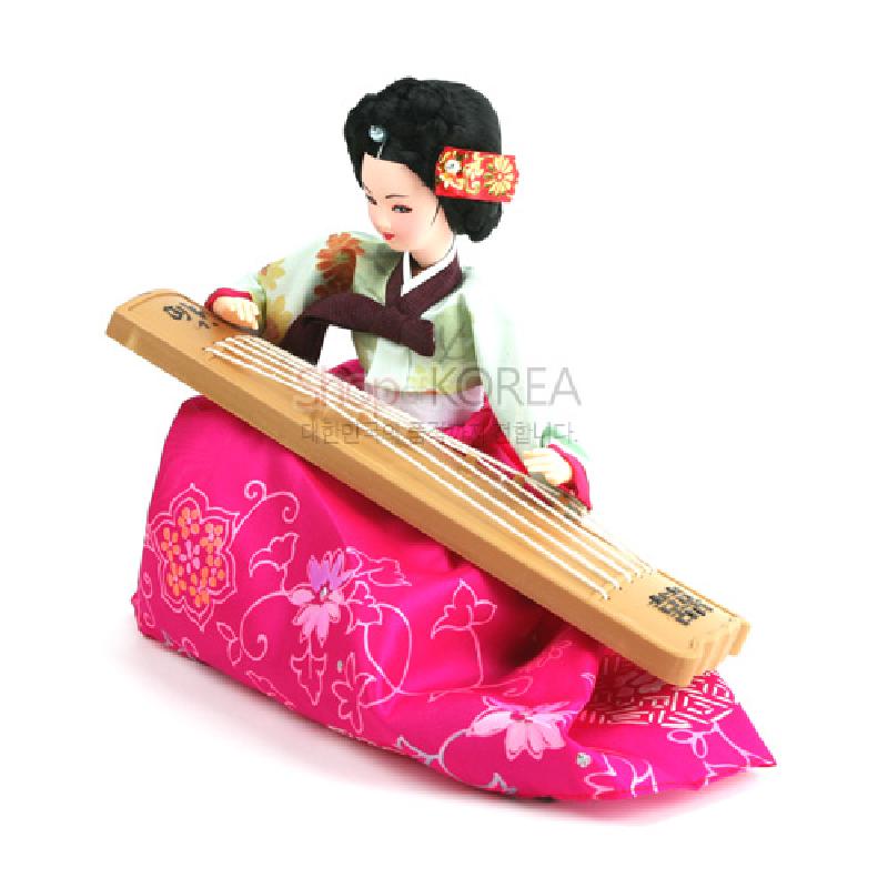 분홍색 꽃무늬 비단치마와 연두빛 저고리를 입고, 나무 재질 가야금을 연주하는 한복 인형 장식.