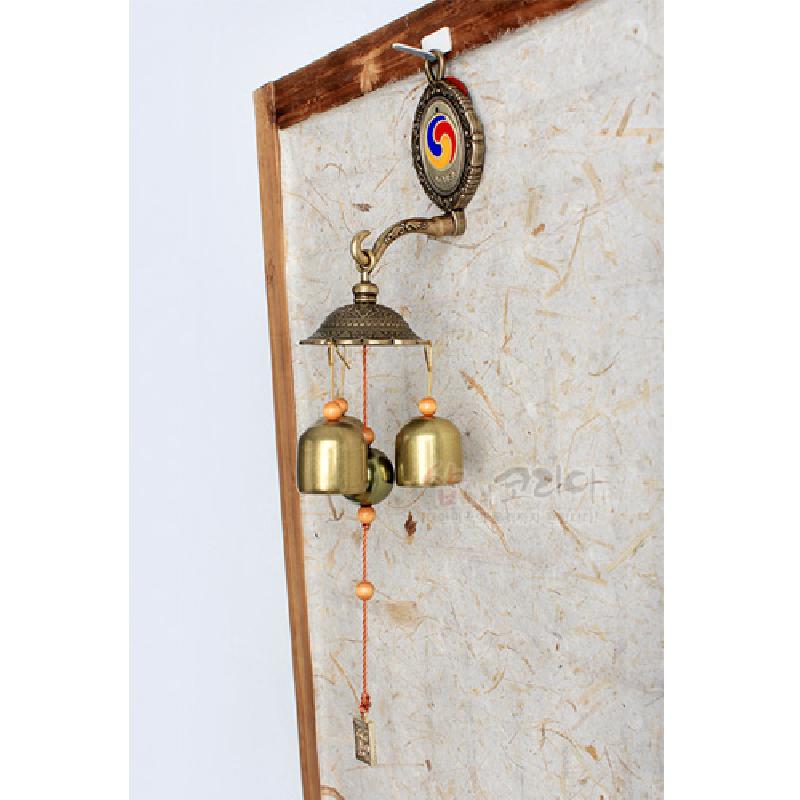 태극 문양 원형 장식과 금속 방울, 나무 구슬, 붉은 매듭줄이 조화된 전통 풍경 장식.