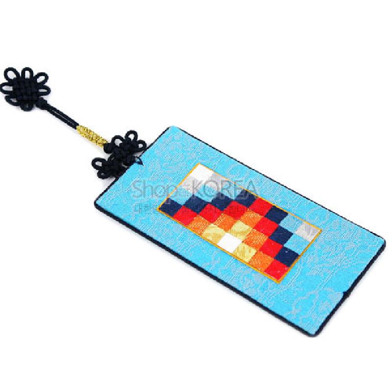 하늘색 비단 바탕에 여러 색 조각보 패턴과 검은 한국 매듭 장식이 어우러진 책갈피.
