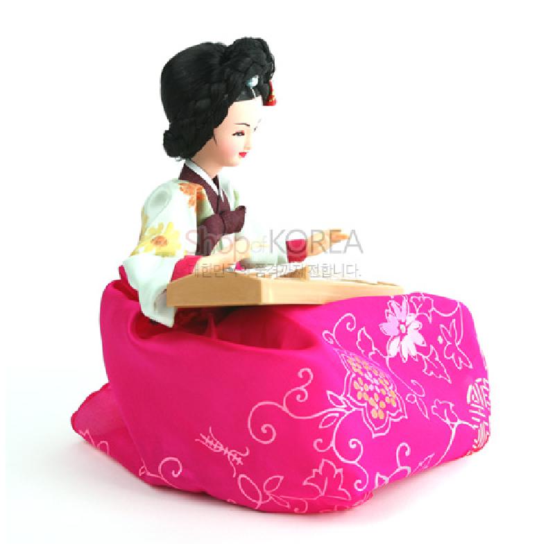 분홍색 비단 치마에 꽃과 덩굴 자수 문양이 더해지고, 전통 가체 머리 장식과 가야금을 들고 있는 한복 인형.