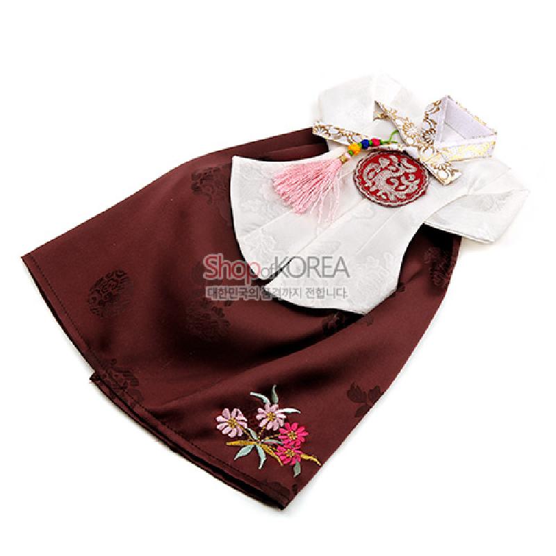 갈색 비단 치마와 흰 저고리로 구성된 한복 형태 와인 커버, 꽃 자수와 전통 문양 인쇄, 오방색 매듭과 분홍 술 장식 특징.