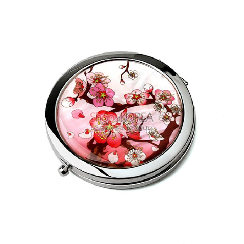 금속 테두리에 자개 장식을 더하고 분홍색 매화와 꽃잎 문양을 채색한 원형 원터치 손거울. 금속 테두리에 자개 장식을 더하고 분홍색 매화와 꽃잎 문양을 채색한 원형 원터치 손거울.