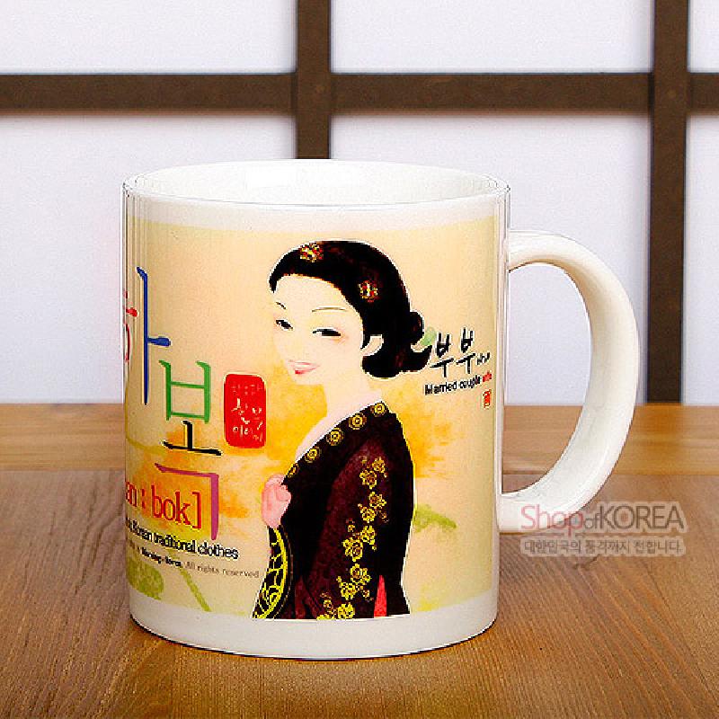 한복 차림 여인 일러스트와 전통 문양, 파스텔톤 배경 색상이 돋보이는 도자기 머그컵. 한복 차림 여인 일러스트와 전통 문양, 파스텔톤 배경 색상이 돋보이는 도자기 머그컵.