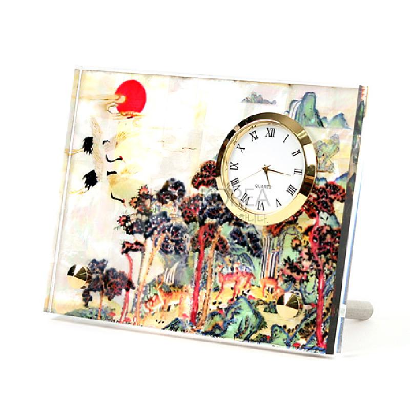 십장생 민화 풍경을 화려한 색감으로 인쇄한 투명 재질 패널과 금색 금속 테두리 아날로그 시계가 결합된 탁상용 시계. 십장생 민화 풍경을 화려한 색감으로 인쇄한 투명 재질 패널과 금색 금속 테두리 아날로그 시계가 결합된 탁상용 시계.