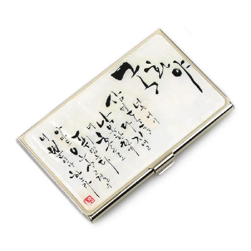 자개 느낌의 흰 바탕 위에 검은 한글 서예 문양을 넣은 금속 테두리 명함집.