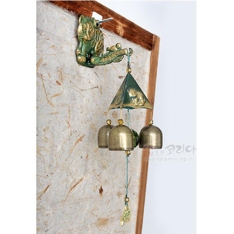 금속 재질의 삼각 지붕과 종, 녹색 호랑이 장식, 매듭끈과 물고기 장식추가 어우러진 풍경종. 금속 재질의 삼각 지붕과 종, 녹색 호랑이 장식, 매듭끈과 물고기 장식추가 어우러진 풍경종.