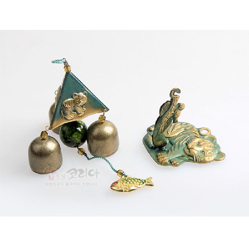 금속 재질 삼각 구조에 호랑이 부조와 녹청색 채색이 더해진 풍경종, 물고기 장식 매듭이 연결된 디자인. 금속 재질 삼각 구조에 호랑이 부조와 녹청색 채색이 더해진 풍경종, 물고기 장식 매듭이 연결된 디자인.