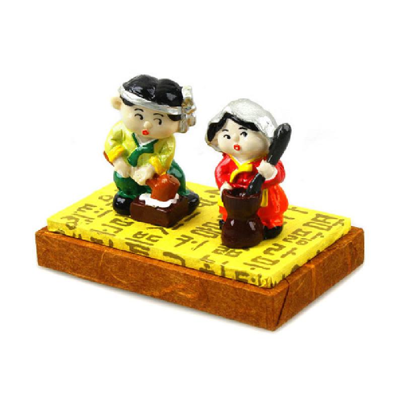 알록달록 채색된 한복 차림 남녀가 절구질을 하는 모습의 레진 인형 장식, 한글 패턴 받침대 특징.