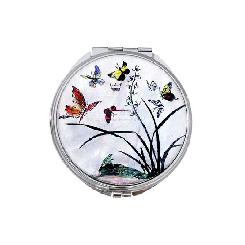 자개 바탕 위에 옻칠 기법으로 표현된 난초와 형형색색 나비 문양이 돋보이는 원형 금속 손거울.