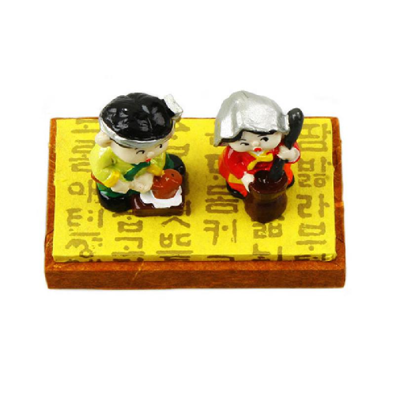 한글 문양 노란 바탕 위에 전통 의상을 입은 절구 치는 남매 도자 미니어처 장식.