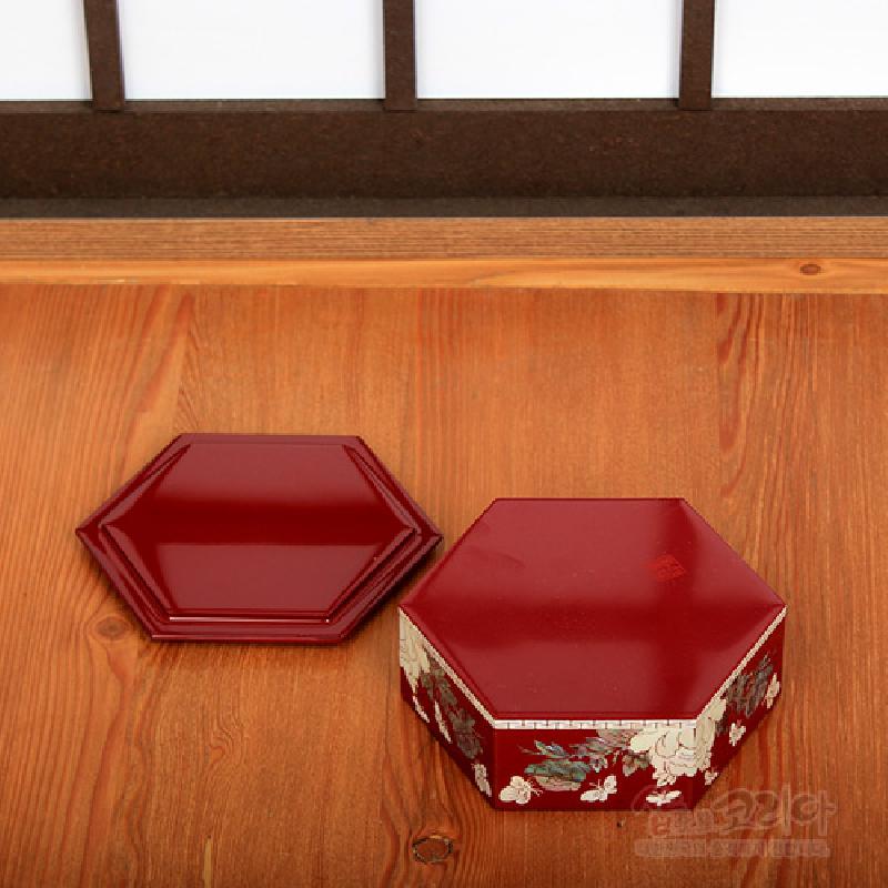 붉은 옻칠을 한 6각 형태의 빈합, 측면에 자개 상감 기법으로 표현된 목단꽃 문양 장식.