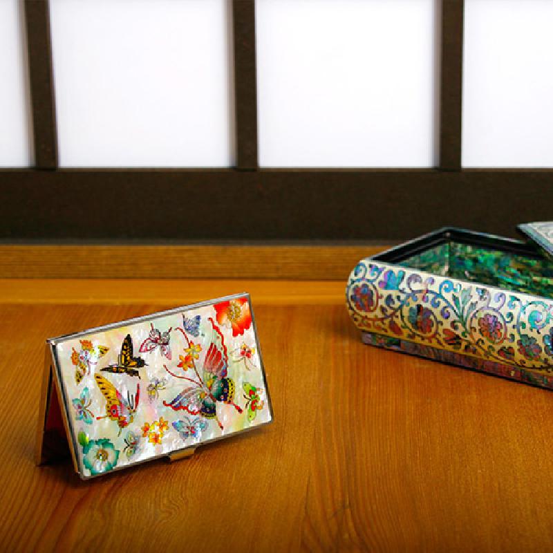 흰색 자개 바탕 위에 다채로운 호랑나비와 꽃 문양을 상감한 금속 테두리 명함케이스. 흰색 자개 바탕 위에 다채로운 호랑나비와 꽃 문양을 상감한 금속 테두리 명함케이스.