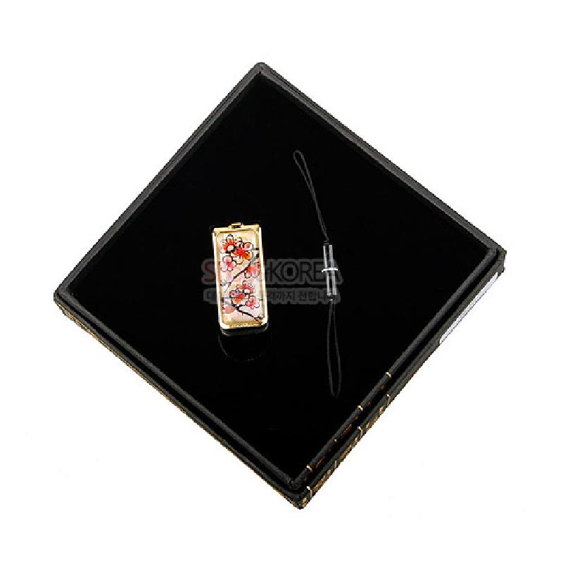 자개 상감 기법으로 장식된 금속 USB 메모리, 붉은 매화와 검은 가지 문양, 금빛 테두리와 대비되는 디자인. 자개 상감 기법으로 장식된 금속 USB 메모리, 붉은 매화와 검은 가지 문양, 금빛 테두리와 대비되는 디자인.