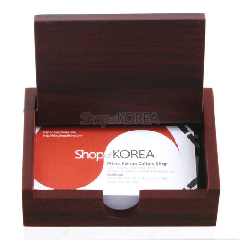 짙은 적갈색 나무 재질의 직사각 명함함으로, 매끄러운 표면과 단순한 라인으로 제작된 뚜껑 여닫이 구조의 디자인이다.