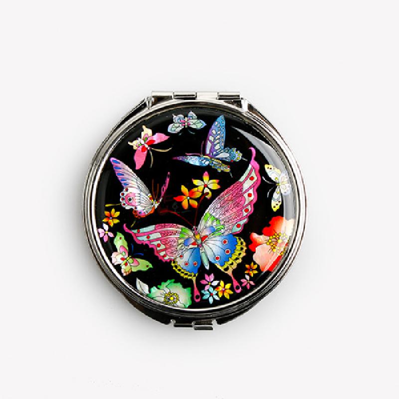 검은 옻칠 바탕 위에 자개 상감으로 표현된 형형색색 호랑나비와 꽃 문양이 돋보이는 금속 테두리 손거울. 검은 옻칠 바탕 위에 자개 상감으로 표현된 형형색색 호랑나비와 꽃 문양이 돋보이는 금속 테두리 손거울.