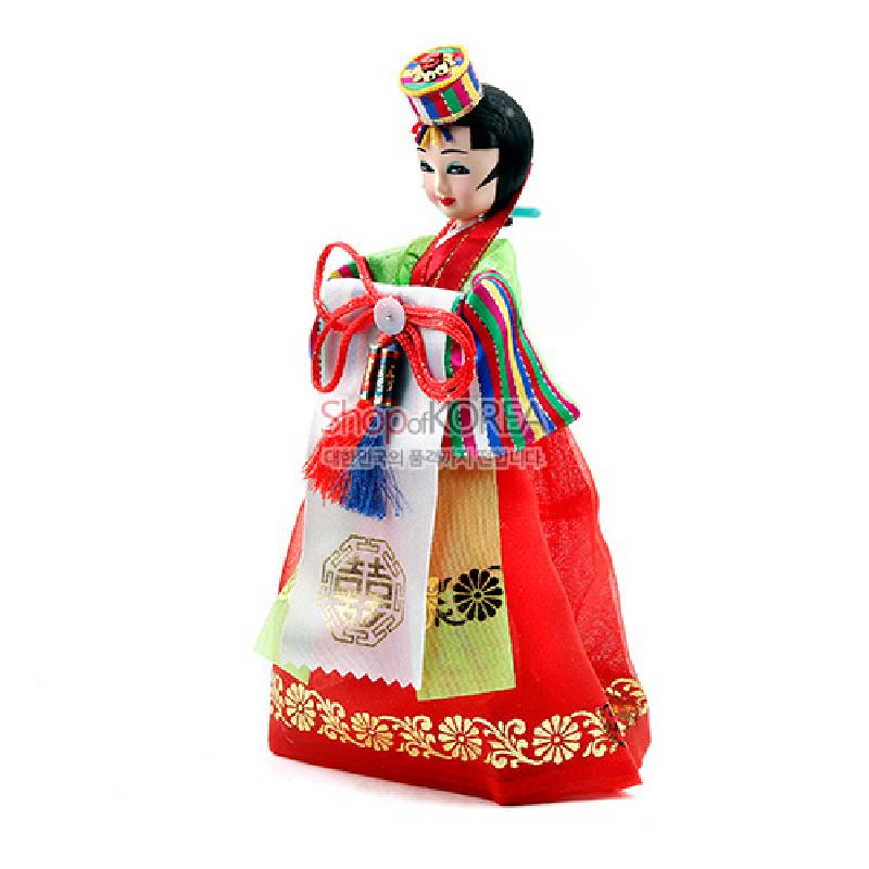 붉은 비단 한복과 금빛 꽃 문양, 오색 단청색 소매와 술 장식 띠를 더한 전통 신부 인형.
