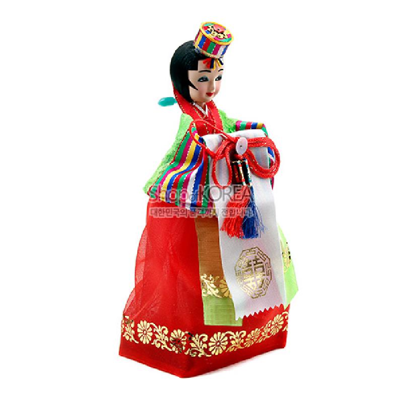 화려한 색동 비단 저고리와 붉은 치마, 금박 꽃무늬 장식과 다채로운 술 장식이 특징인 전통 신부 한복 인형.