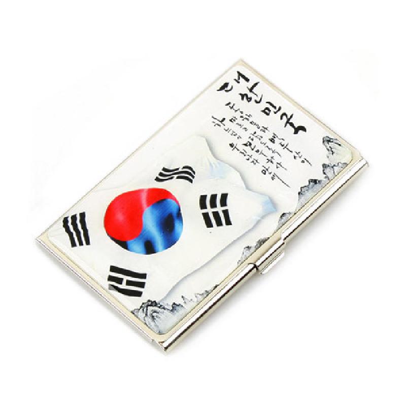 금속 재질 위에 태극기 문양과 휘날리는 국기 표현, 서예 글귀가 인쇄된 직사각형 명함집.