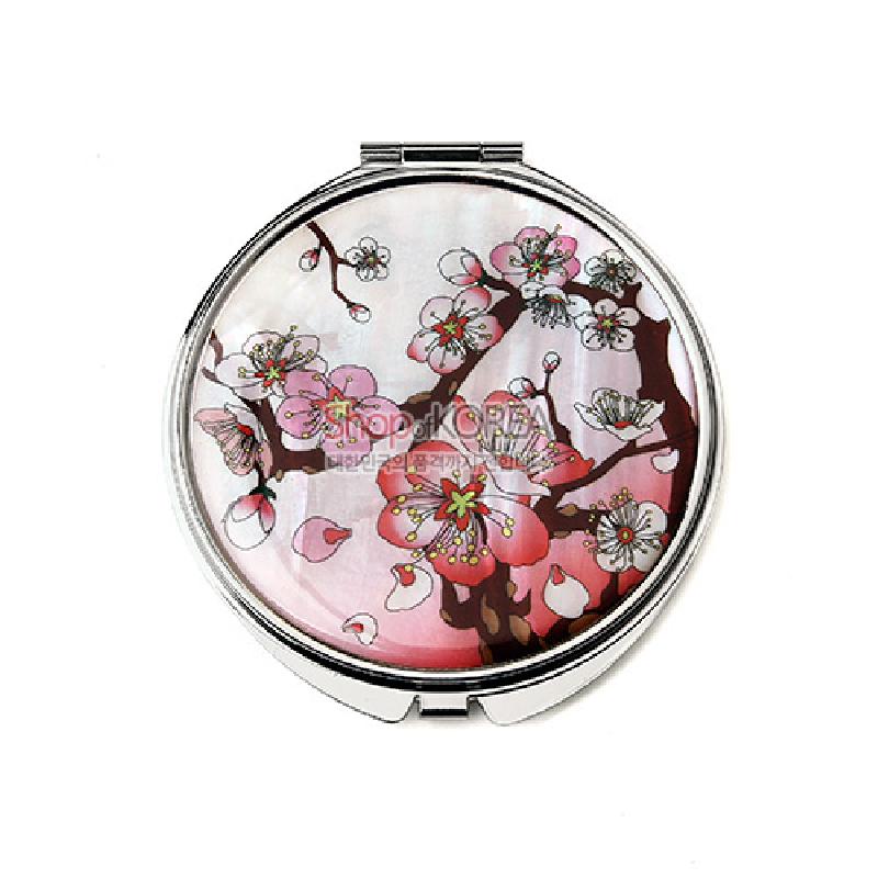 자개 바탕에 분홍색과 흰색 매화꽃 문양이 그려진 원형 금속 손거울.