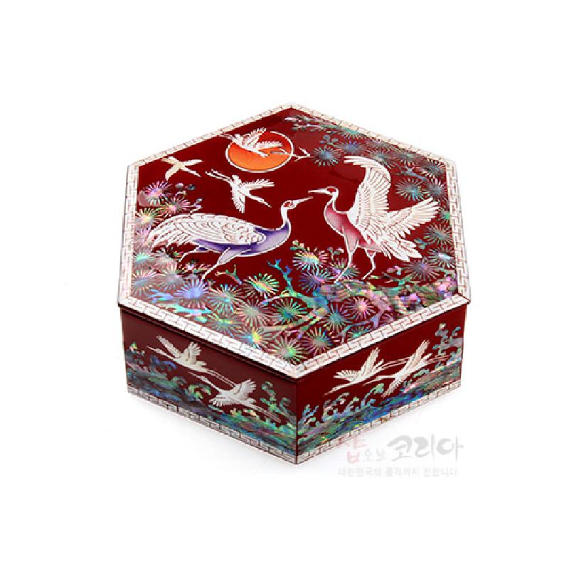 붉은 옻칠 바탕에 자개 상감 기법으로 송학과 소나무, 해를 섬세하게 표현한 6각 형태 공예 보관함.