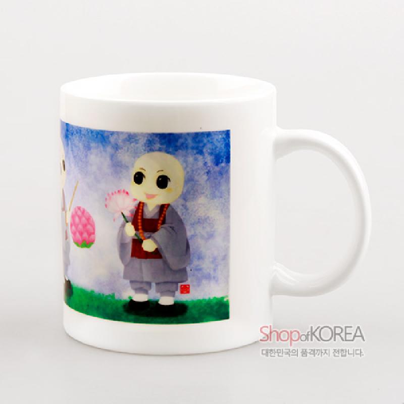 백색 도자 재질에 동자승과 연등을 그린 수채화풍 일러스트 장식이 특징인 머그컵.