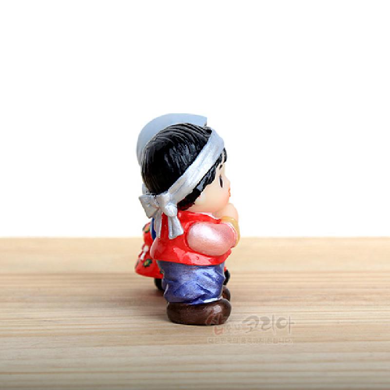 채운 머리띠와 붉은 조끼, 보라색 바지를 입고 다채로운 복주머니를 멘 소형 민속 인형 장식. 채운 머리띠와 붉은 조끼, 보라색 바지를 입고 다채로운 복주머니를 멘 소형 민속 인형 장식.