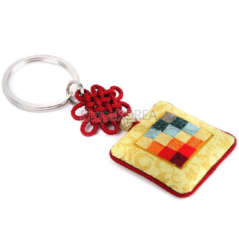 금속 고리와 붉은 전통 매듭, 황색 비단 바탕 위 여러 색 조각보 누빔 장식이 특징인 열쇠고리.