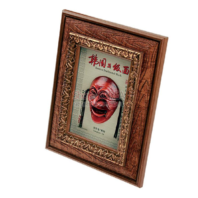 나뭇결 무늬의 목재 액자에 황금색 부조 장식 테두리와 붉은색 하회 양반탈 입체 장식이 어우러진 인테리어 소품.