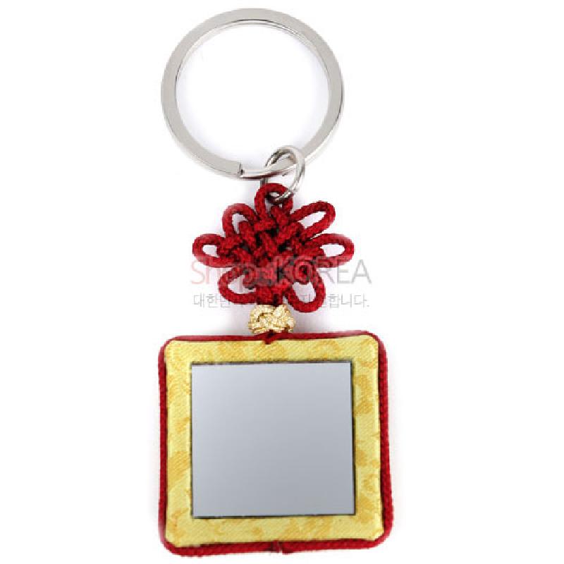 황색 비단 누비 테두리에 사각 거울이 달린 장식에 붉은 전통 매듭과 금속 링으로 구성된 열쇠고리.