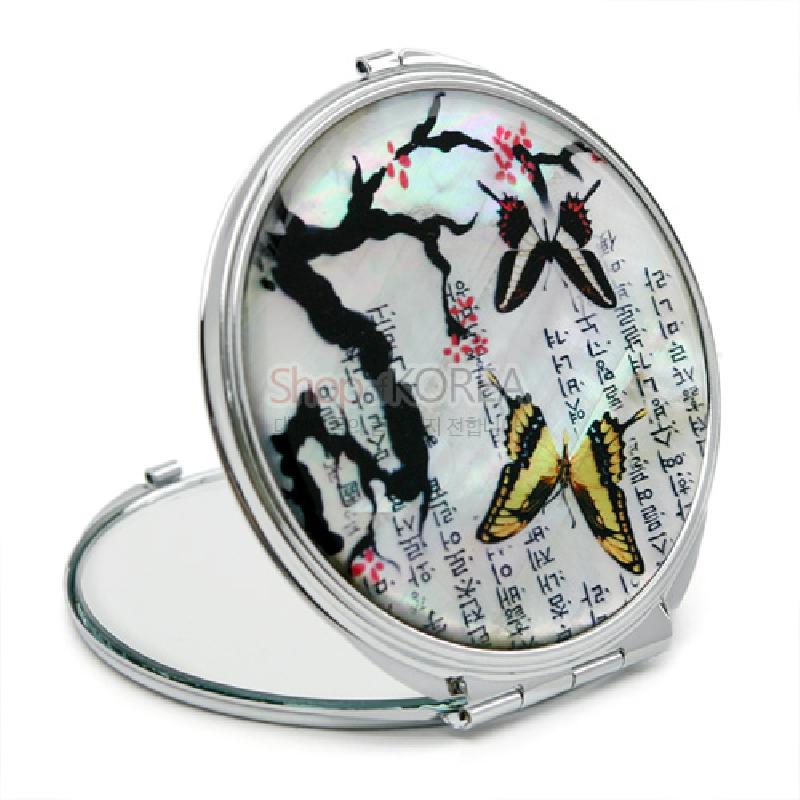 자개 바탕에 매화나무와 나비, 한글 서체 문양을 담은 금속 테두리 손거울.