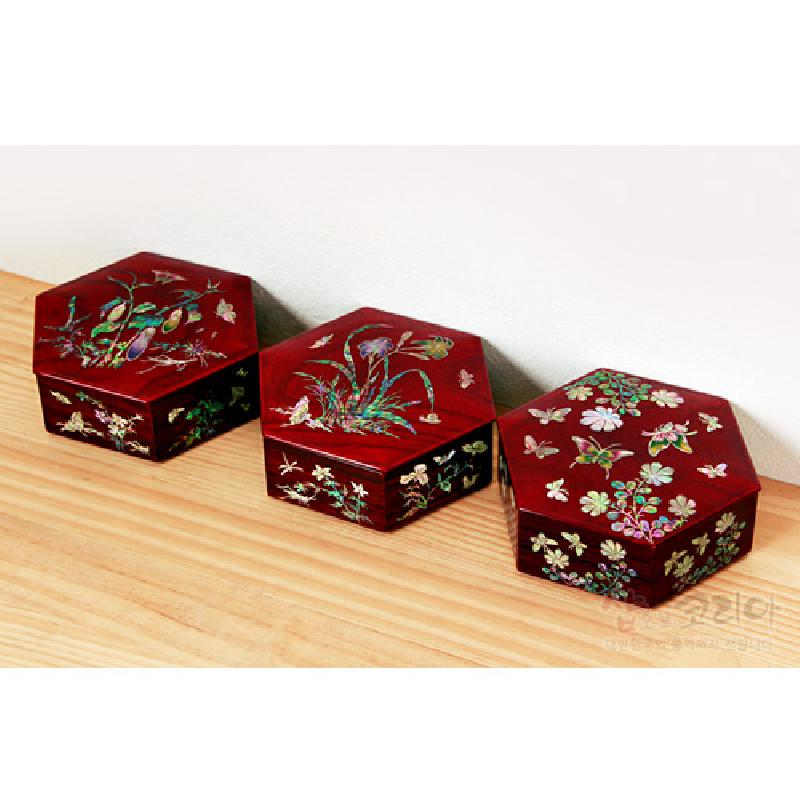 붉은 옻칠 바탕 위에 자개 상감 기법으로 원추리와 꽃, 나비 문양을 섬세하게 표현한 육각형 나전함.