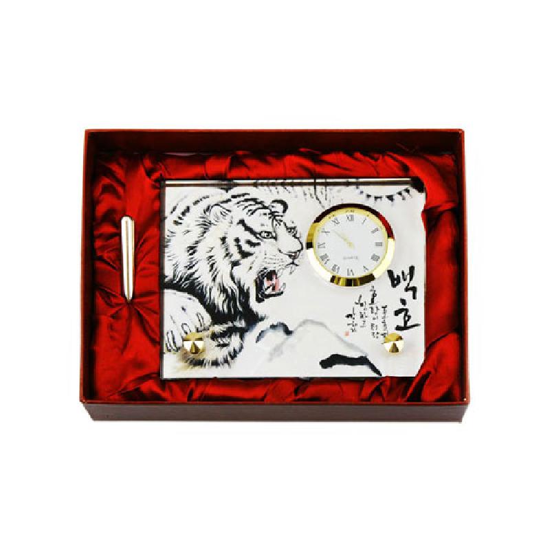 백호 수묵화와 한글 서체가 인쇄된 직사각형 패널에 금속 테두리 원형 시계가 결합된 탁상용 시계.