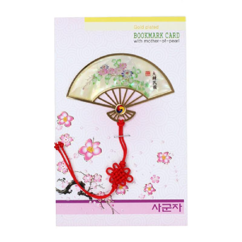 자개로 장식된 부채 모양 금속 책갈피에 국화와 꽃문양이 섬세하게 그려지고 붉은 전통 매듭 장식이 더해진 디자인.
