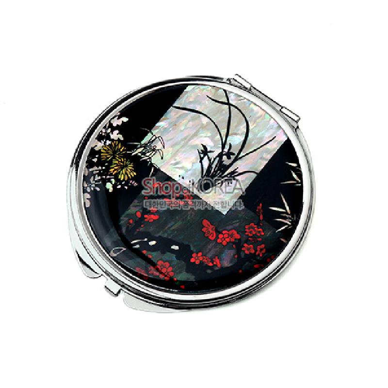 자개 상감 기법으로 사군자 문양을 넣은 금속 테두리 원형 손거울, 검은 옻칠 바탕에 붉은 꽃과 색채 대비가 돋보이는 디자인.