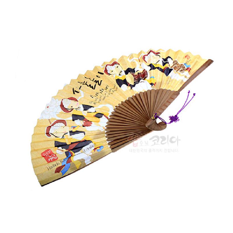 연한 노랑 종이 위에 사물놀이 인물 일러스트와 한글 글씨가 인쇄된 나무살 접이부채, 보라색 매듭 장식 특징. 연한 노랑 종이 위에 사물놀이 인물 일러스트와 한글 글씨가 인쇄된 나무살 접이부채, 보라색 매듭 장식 특징.