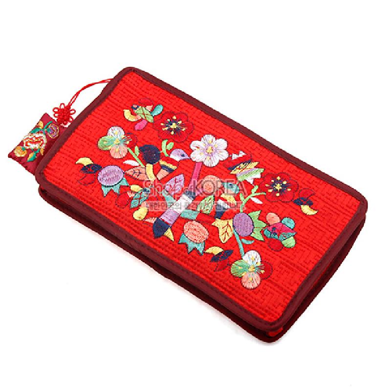 붉은 비단 바탕에 누비 처리된 직사각 파우치, 다채로운 꽃과 나비 자수 문양과 전통 매듭 장식이 특징인 제품.