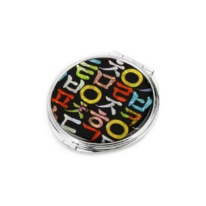 검은 바탕 위에 다채로운 색상의 한글 자개 상감 문양이 들어간 금속 테두리 원형 손거울.