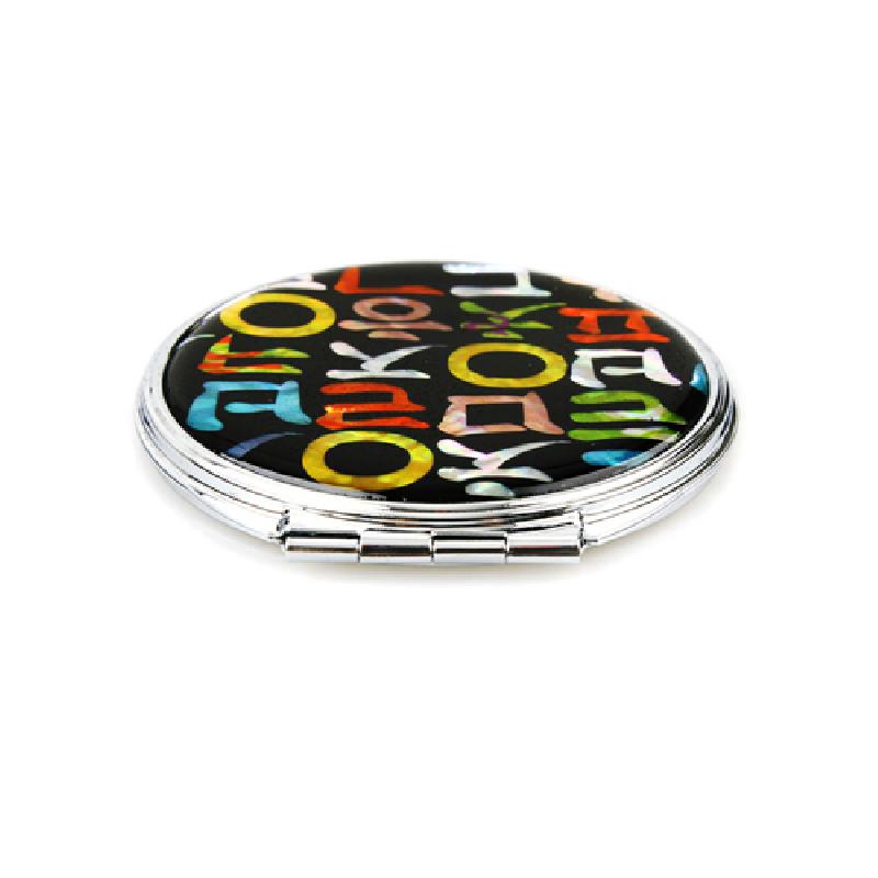 검은 바탕 위에 다채로운 색상의 한글 자모 문양이 삽입된 금속 테두리 손거울.