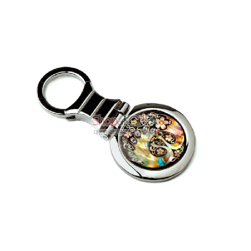 금속 테두리에 자개 상감 기법으로 공작과 꽃문양을 넣은 원형 장식 열쇠고리.